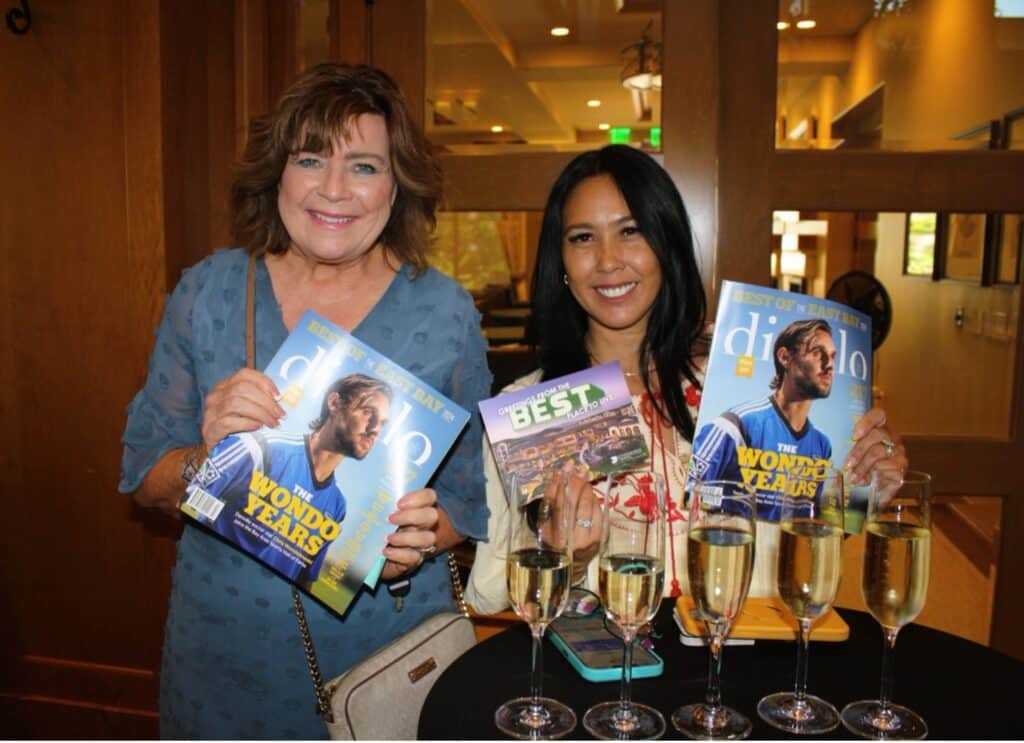 Two women hold up magazines