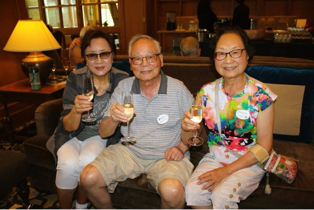 Three seniors sit on a couch and toast with champagne